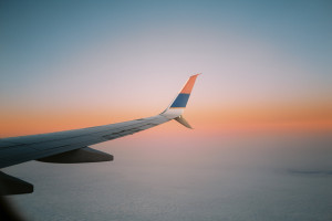 View of a sunrise and airplane wing, seen from a plane window.